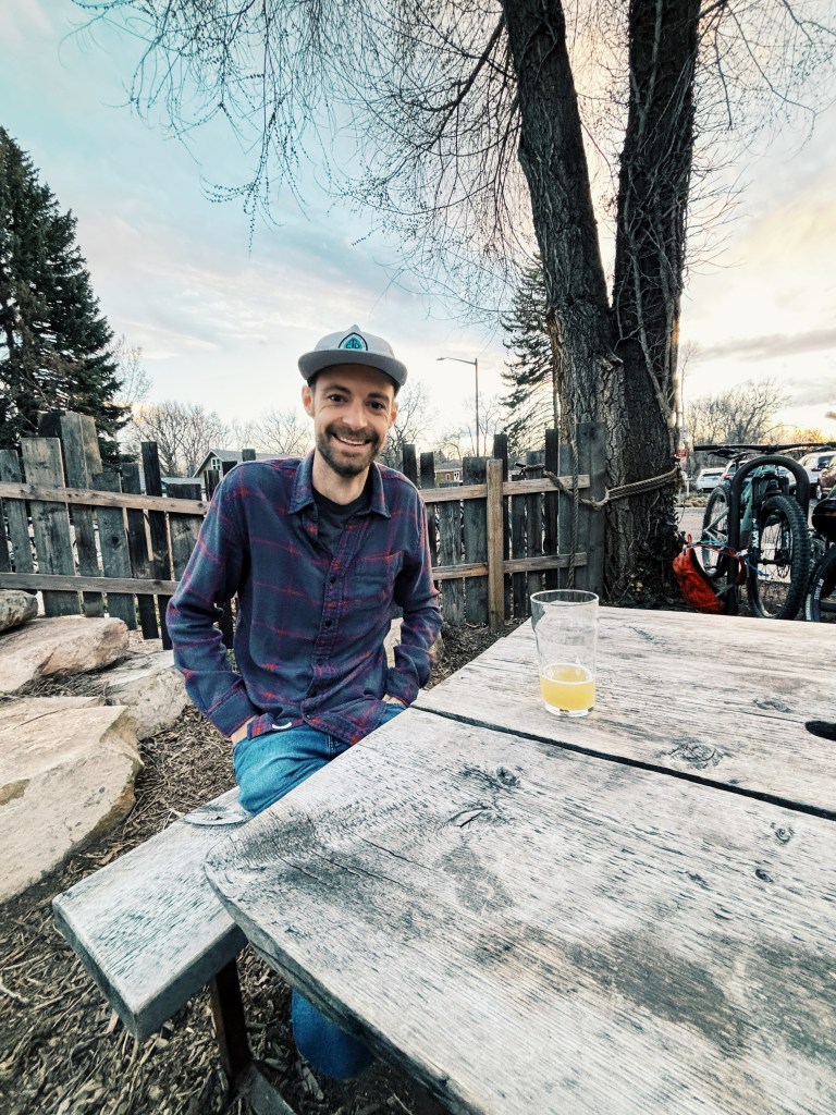 Evan Nelson Senie sits at a wooden outdoor table